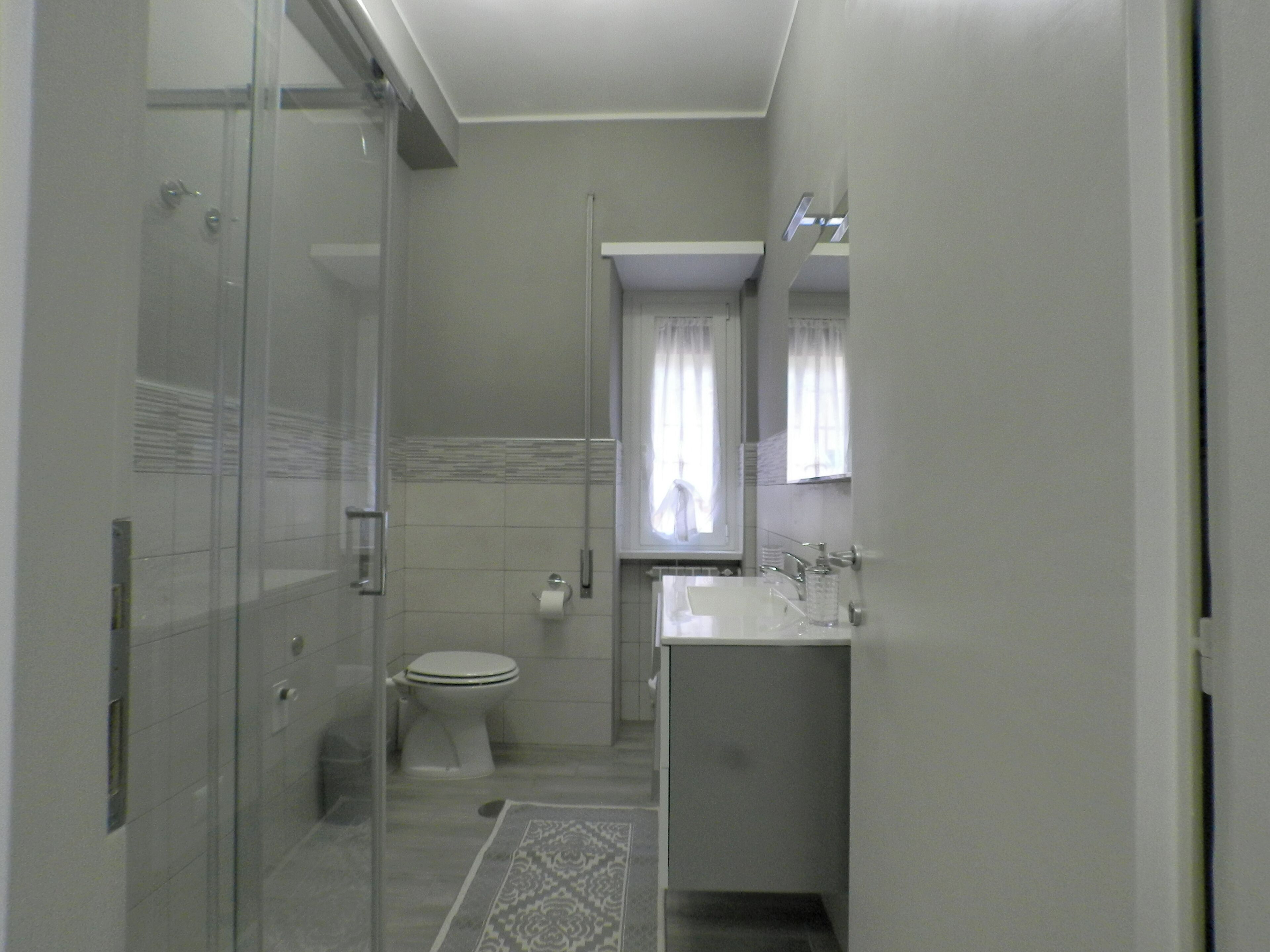 A modern bathroom with a glass shower enclosure, a toilet, and a sink with a mirror.
