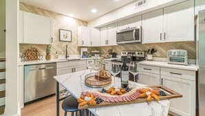A modern kitchen with white cabinets, a microwave, a built-in oven, and a marble island with a charcuterie board. - RIDGEVIEW RETREAT | HOT TUB | FIRE PIT AND GAMES (Clarkesville)