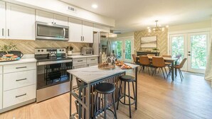 A modern kitchen with built-in appliances, a dining area with a herringbone-patterned wall, and a large window. - RIDGEVIEW RETREAT | HOT TUB | FIRE PIT AND GAMES (Clarkesville)