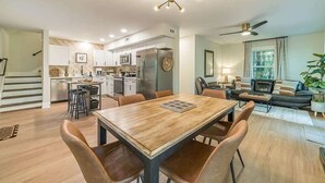 A modern kitchen with a central island, a dining area with a wooden table and leather chairs, and a living area with a sofa and a plant. - RIDGEVIEW RETREAT | HOT TUB | FIRE PIT AND GAMES (Clarkesville)