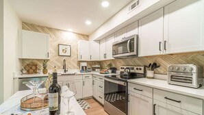 A modern kitchen with white cabinets, a microwave, an oven, and a toaster. - RIDGEVIEW RETREAT | HOT TUB | FIRE PIT AND GAMES (Clarkesville)