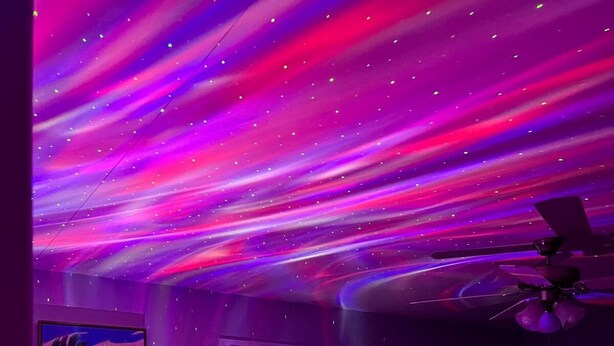 Una camera da letto con un letto, una ventola a soffitto, una finestra con persiane e un quadro appeso al muro.