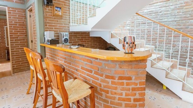 A kitchen with a brick island, wooden chairs, and a staircase leading to an upper level. - New Family House. Pool & BBQ Area (Yautepec)