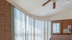A room with a curved ceiling, a ceiling fan, a patterned sofa, and a large window with vertical blinds. - New Family House. Pool & BBQ Area (Yautepec)