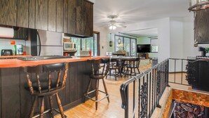 A kitchen with a wooden bar, bar stools, a ceiling fan, and a dining area with a table and chairs. - Waterfront Berry Lake Getaway w/ Sunroom! (Gillett)
