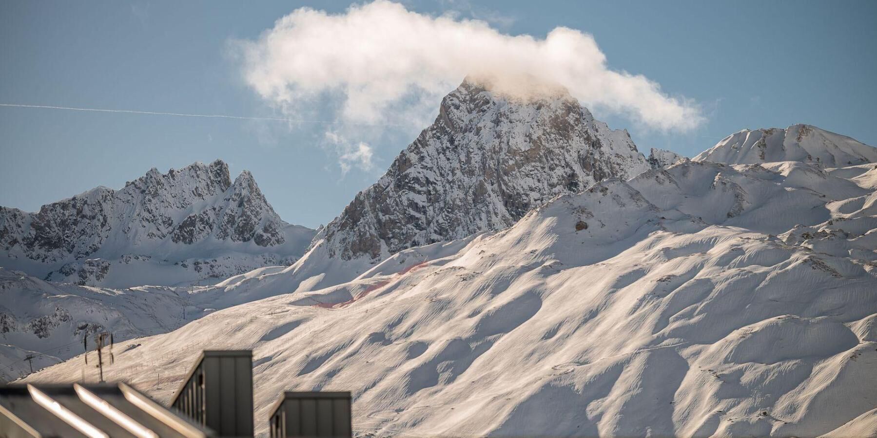 A snow-covered mountain landscape with a prominent peak and a ski lift in the foreground.