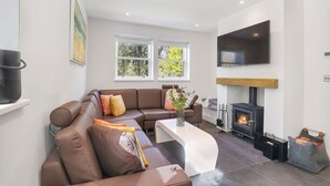 A modern living room with a brown leather sofa, a white coffee table, and a fireplace.