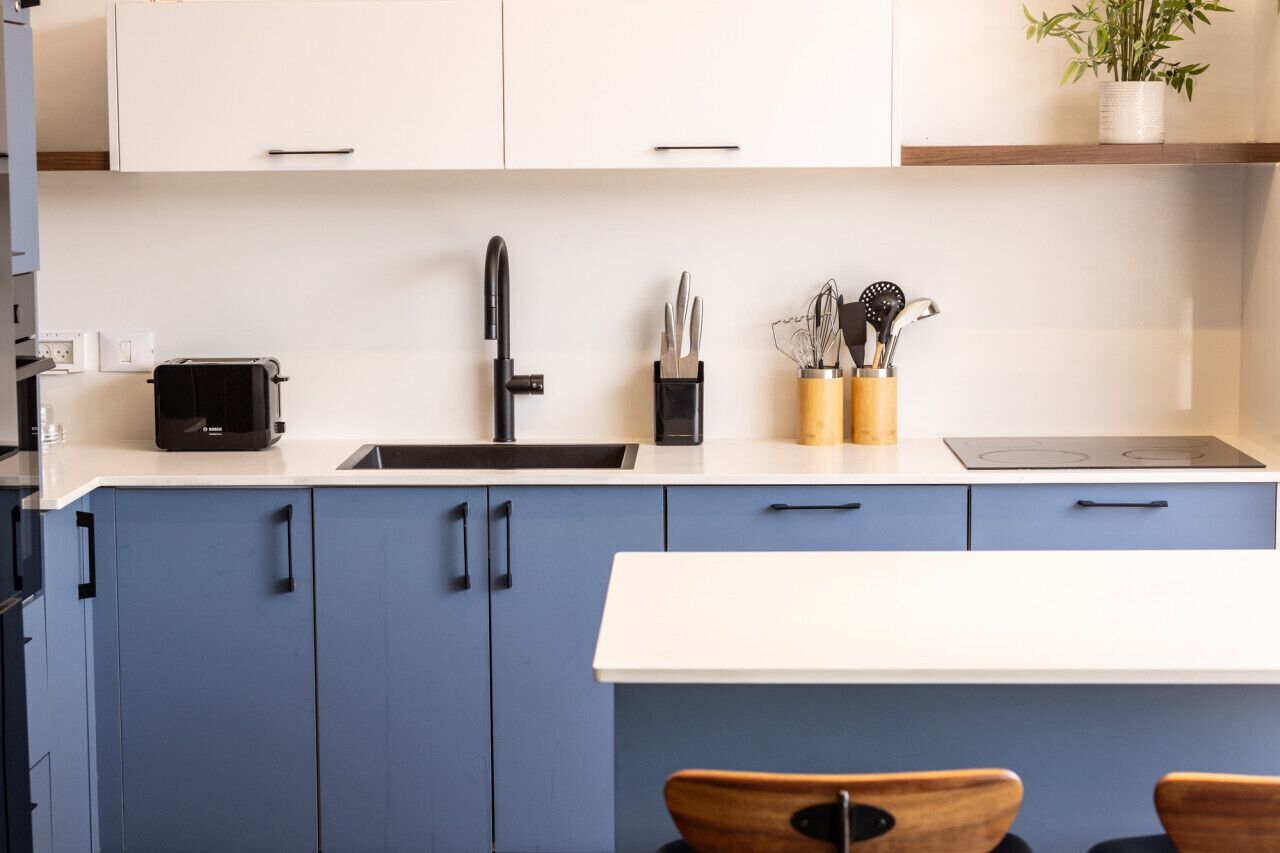 Een moderne keuken met een zwarte kraan, een broodrooster en keukengerei op het aanrecht.