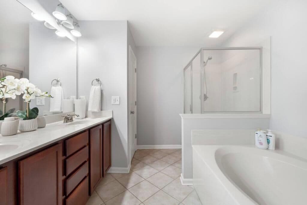 Een moderne badkamer met een grote spiegel, een bad en een douche.