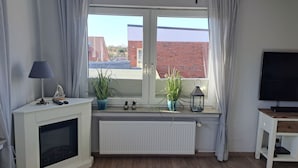 En moderne stue med pejs, fjernsyn og et vindue med gardiner.