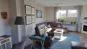 En moderne stue med en lædersofa, et sofabord, et tilhørende bord og en blå måtte.