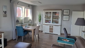 En stue med spiseplads, et skab med glaslåger og en dør.