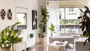 A modern living room with a sofa, a coffee table, and several potted plants. - Heart of TLV Elegant Home by Sea N' Rent (Tel Aviv)