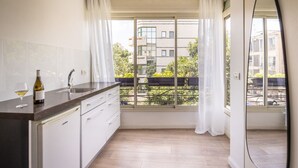 A modern kitchen with a large window, a built-in oven, and a wine bottle on the counter. - Heart of TLV Elegant Home by Sea N' Rent (Tel Aviv)