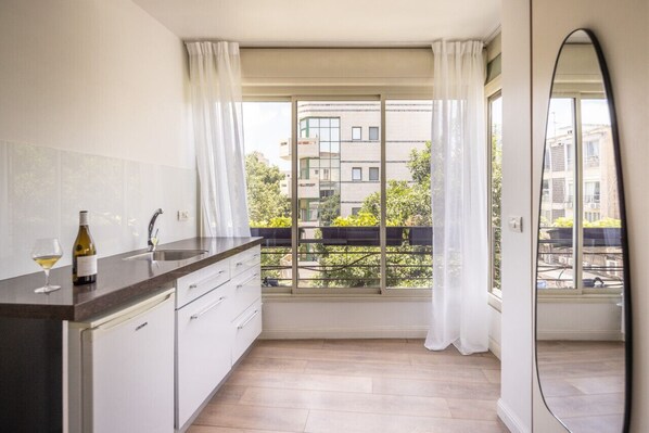 A modern kitchen with a large window, a built-in oven, and a wine bottle on the counter. - Heart of TLV Elegant Home by Sea N' Rent (Tel Aviv)