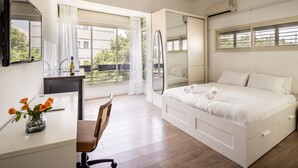 A bedroom with a bed, a desk, a chair, a mirror, and a window. - Heart of TLV Elegant Home by Sea N' Rent (Tel Aviv)