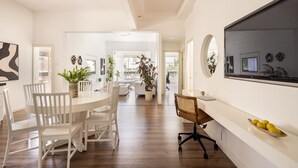 A spacious room with a dining area, a large TV mounted on the wall, and several potted plants. - Heart of TLV Elegant Home by Sea N' Rent (Tel Aviv)