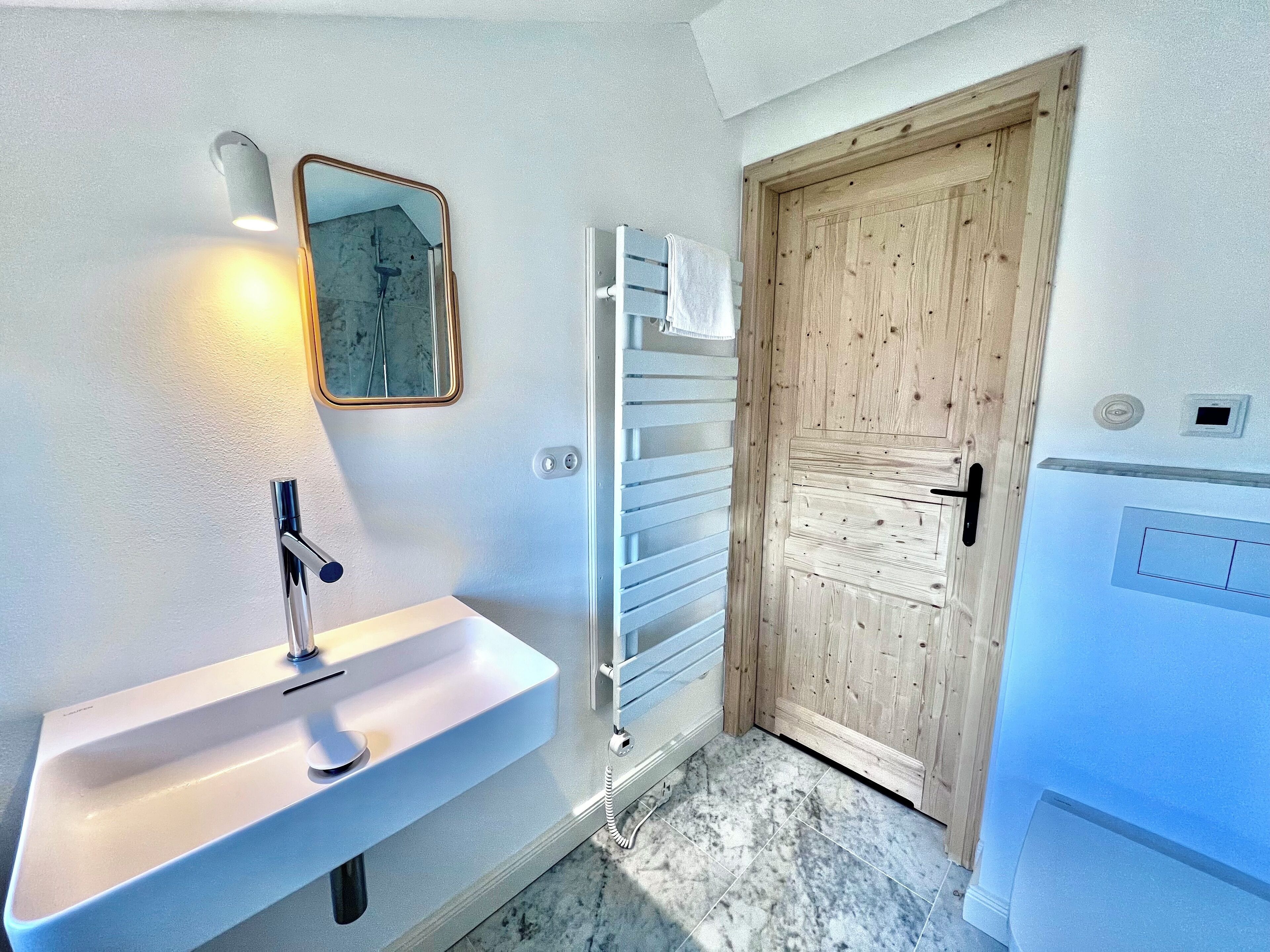 A bathroom with a white sink, a mirror, and a wooden door.