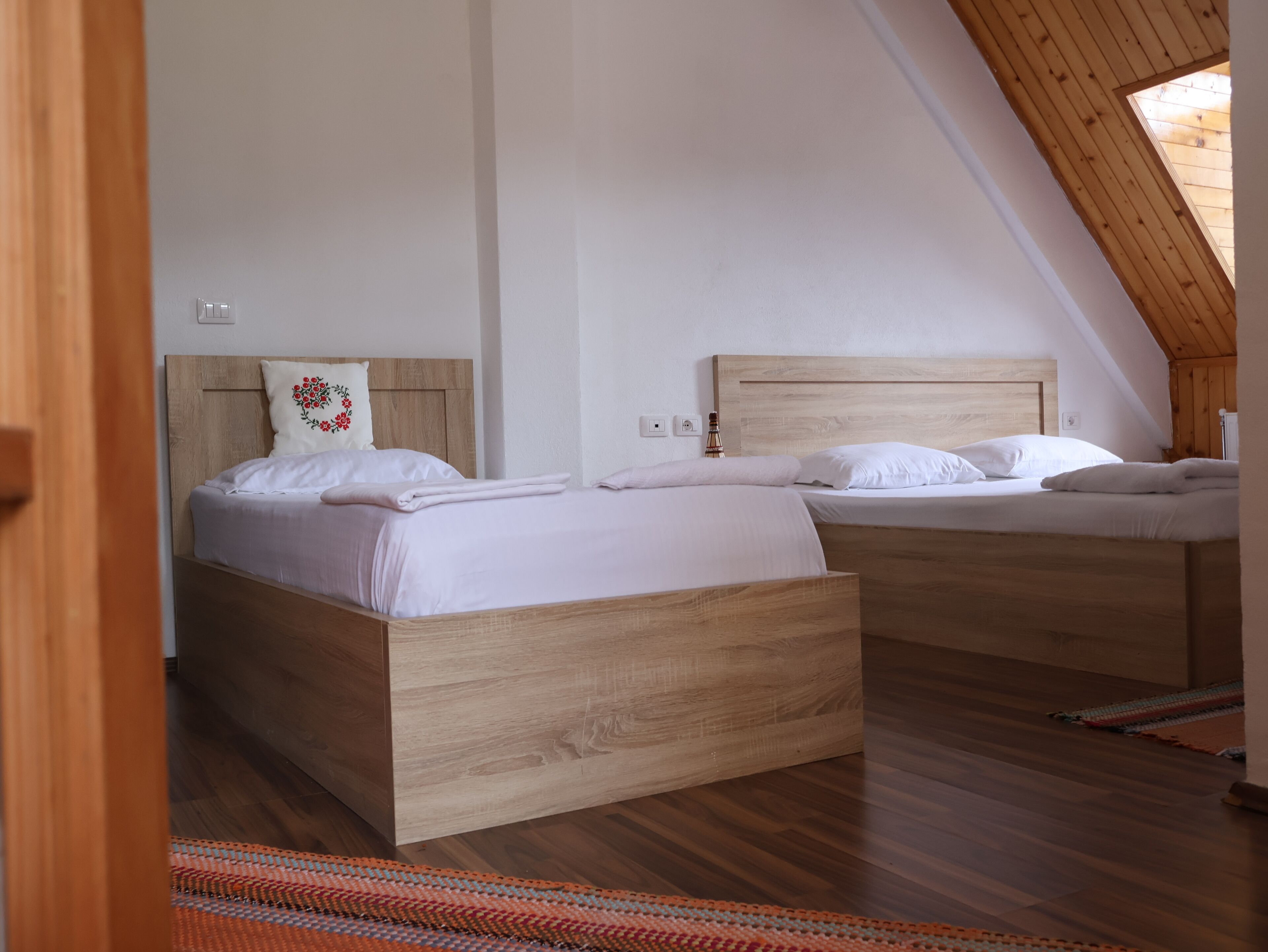 Une chambre à coucher avec deux lits en bois, un plafond en pente et une fenêtre bien visible.
