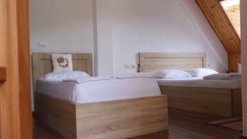 Une chambre à coucher avec deux lits en bois, un plafond en pente et une fenêtre bien visible.