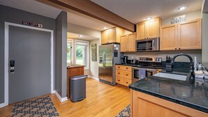 A modern kitchen with wooden cabinets, stainless steel appliances, and a granite countertop. - New! Mountain View Chalet w/ Hot Tub & Fireplace (McHenry)