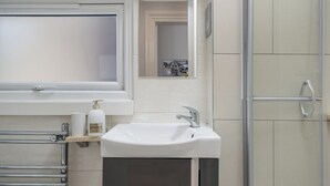 Une salle de bain moderne avec un lavabo blanc, un miroir et une cabine de douche.