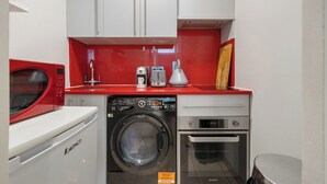 Une cuisine compacte équipée d’un lave-linge, d’un four à micro-ondes, d’un grille-pain et d’un four.