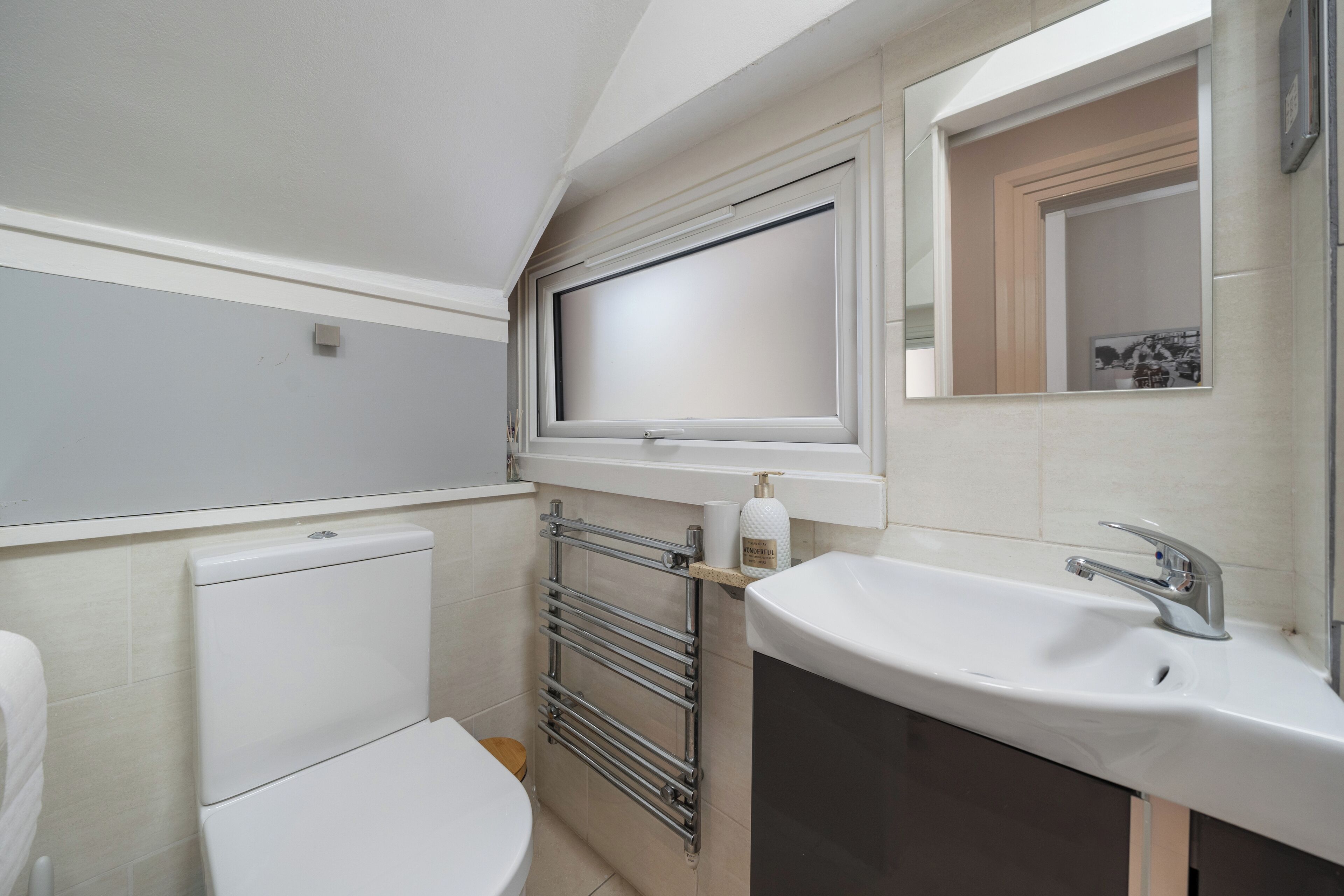 Une salle de bain moderne équipée de toilettes, d’un lavabo, d’un porte-serviettes et d’un miroir.