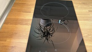 Une plaque de cuisson à induction noire, avec un panneau de commande intégré dans un plan de travail en bois.