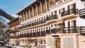 A hotel with a traditional alpine architectural style, featuring balconies and a restaurant on the ground floor. - Hotel Las Donnas (Saint-Etienne-de-Tinee)
