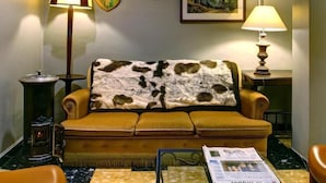 A cozy living room with a sofa, a fireplace, a painting, and a lamp. - Hotel Las Donnas (Saint-Etienne-de-Tinee)
