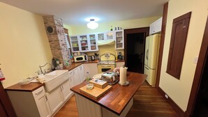 Una cocina compacta con armarios blancos, encimera de madera y pared decorativa de ladrillo.