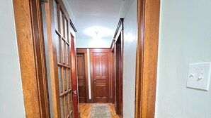 Un pasillo con piso de madera, alfombra estampada y puertas de madera.