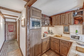 A kitchen with wooden cabinets, a built-in oven, a microwave, and a sink.