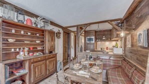 A rustic kitchen with wooden cabinets, a dining table set with dishes, and a plaid bench. - 100m from ski slopes, balcony, tv, ski locker, 56m², Tignes (Tignes)