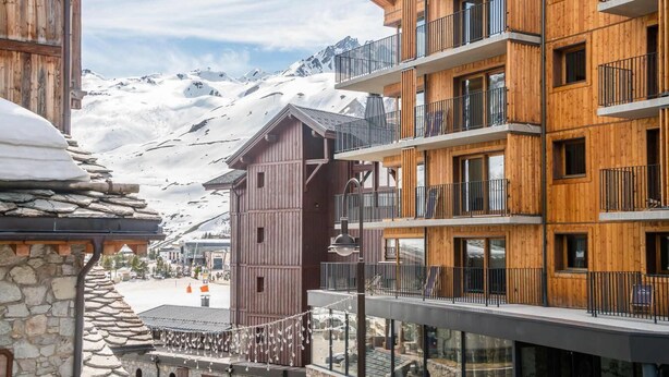 A multi-story wooden building with balconies, set against a snowy mountain backdrop. - 100m from ski slopes, balcony, tv, ski locker, 56m², Tignes (Tignes)