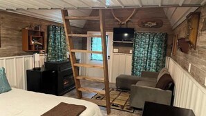 Een gezellige slaapkamer met een bed, een ladder, een televisie, een open haard en een bank.
