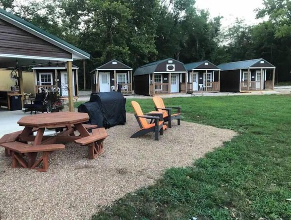 Une terrasse avec une table en bois et deux chaises, entourée d’une zone recouverte de gravier et d’une pelouse.