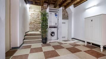 A laundry room with a washing machine and dryer, a potted plant, and a checkered floor.