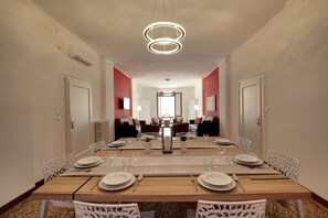 A dining room with a long table set for six, white chairs, and a modern chandelier. - Accademia Opera Deluxe by Wonderful Italy (Venice)