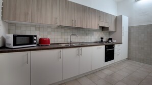 Eine moderne Küche mit weißen Schränken, einer Mikrowelle, einem roten Toaster, einem Spülbecken und einem Geschirrspüler.
