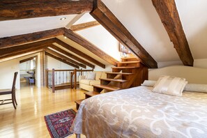 A bedroom with a large bed, a wooden staircase, and a view of the kitchen. - Al Campanile View Terrace by Wonderful Italy (Venice)