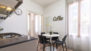 A modern kitchen with a stove, a dining table with chairs, a clock, and a wall-mounted sign that says "Coffee". - Arsenale Canal View 1 by Wonderful Italy (Venice)