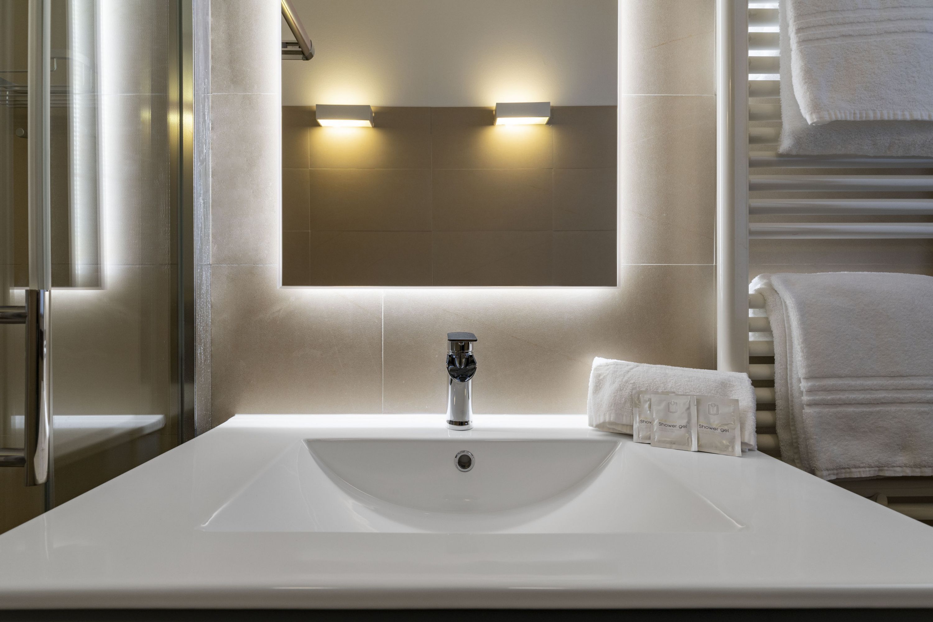 Ein modernes Badezimmer mit einem großen weißen Waschbecken, einem Spiegel und zwei Wandleuchten.