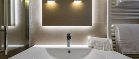 Ein modernes Badezimmer mit einem großen weißen Waschbecken, einem Spiegel und zwei Wandleuchten.