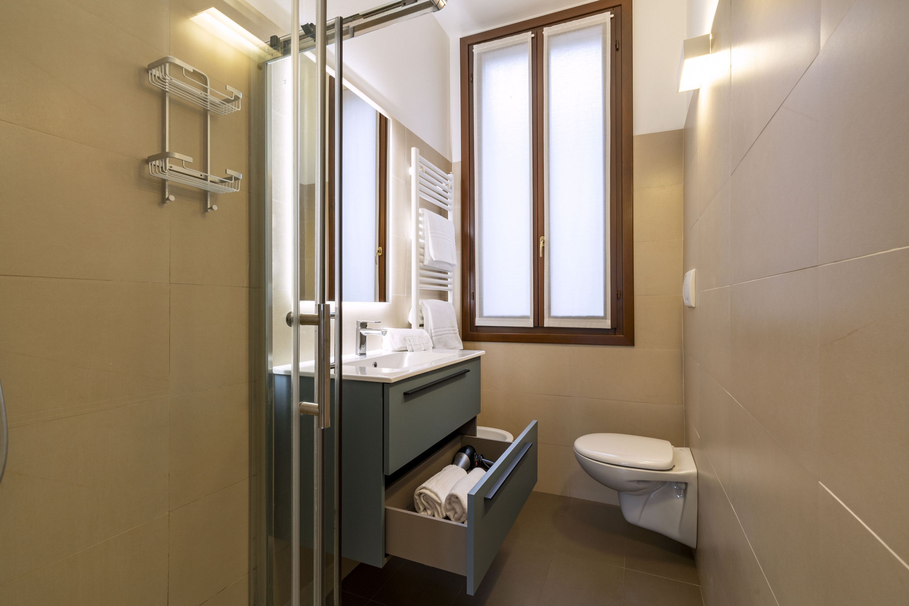 Un baño moderno con cabina de ducha de vidrio, lavabo integrado con espejo y un inodoro.