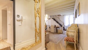 A room with a large ornate mirror, a staircase leading to another level, and a dining area with chairs and a table. - Gondola Luxury Apartment by Wonderful Italy (Venice)