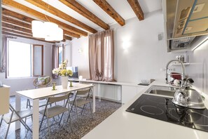 A modern kitchen with a white countertop, stainless steel appliances, and a black induction cooktop. - Ca Fosca Home by Wonderful Italy (Venice)
