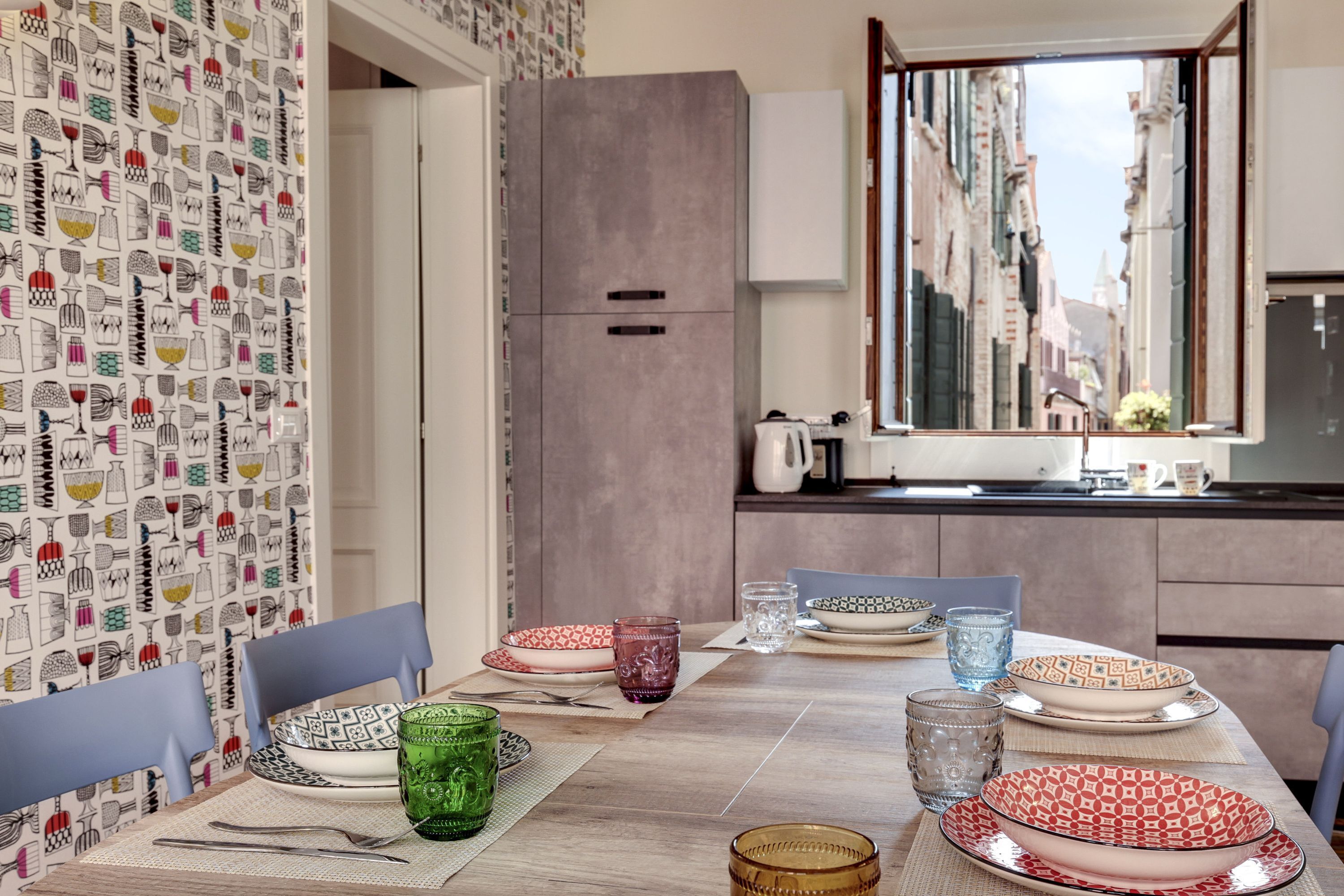 A dining area with a table set for four, featuring patterned plates and glassware.