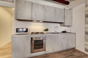 Een moderne keuken met een ingebouwde magnetron, gasfornuis, oven en een roestvrijstalen spoelbak.